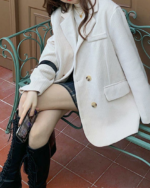 Une femme assise sur un banc vert qui porte un blouson chic vintage en velours côtelé beige