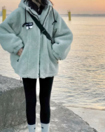 Blouson polaire vert épais à capuche pour femme sur une femme sur fond de mer