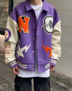Un homme dans la rue qui porte un blouson violet style universitaire américain avec des lettres brodées