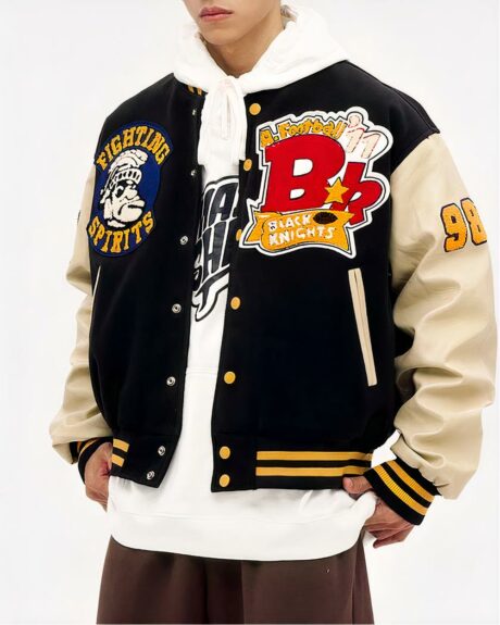 Un homme qui porte un blouson teddy style hip hop noir avec des lettres et dessins brodés sur un fond blanc