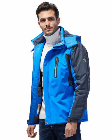 Un homme qui porte un blouson ski imperméable bleu et noir sur un fond blanc