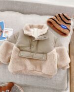Blouson à enfiler en fourrure pour bebe garçon posé à plat sur un coussin.