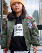 Un petit garçon qui porte un blouson aviateur kaki patchwork