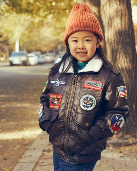 Une petite fille qui porte un blouson vintage aviateur à patchwork dans la rue