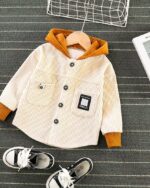 Blouson à capuche en velours beige pour enfant posé sur fond gris