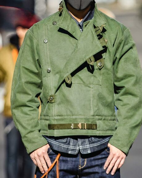 Blouson bombardier kaki vintage en coton pour homme porté par un homme sur fond d'une rue floutée