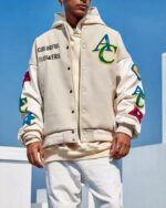 Blouson bomber homme avec flocage de fleurs brodées, avec logo AC devant, de couleur beige avec manche blanche, porté par un homme debout
