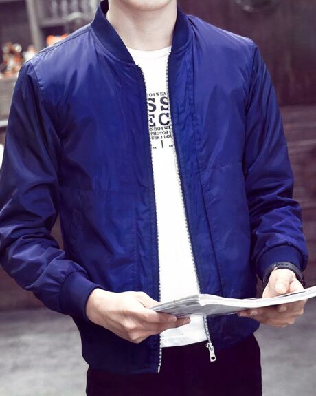 Blouson bomber homme, coupe-vent et décontracté, de couleur avec une fermeture à glissière centrale, porté par un homme avec un magazine dans les mains