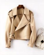Blouson cuir femme beige coupe aviateur sophistiqué posé à plat près d'une sac à main