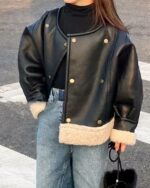 Blouson cuir fille, avec fausse fourrure blanche en bas du blouson, blouson de couleur noir, porté par une fille debout dans la rue avec une main dans la poche