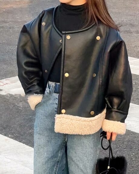 Blouson cuir fille, avec fausse fourrure blanche en bas du blouson, blouson de couleur noir, porté par une fille debout dans la rue avec une main dans la poche