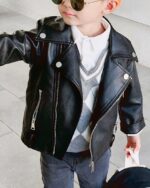 Un petit garçon portant un blouson rockeur noir en simili cuir
