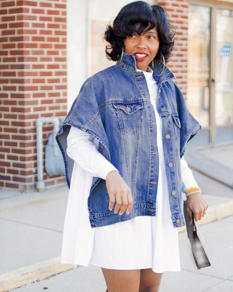 Blouson en jean court à manches chauve-souris pour femme porté par une femme sur fond d'une rue avec un bâtiment en briques