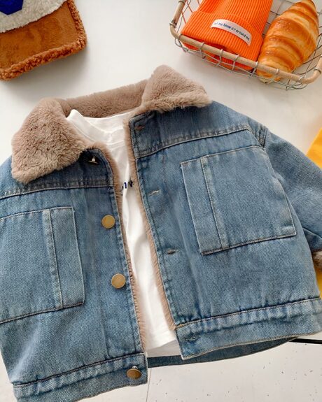 Blouson en jean doublé de fourrure pour bébé garçon posé au sol.