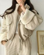 Blouson matelassé femme court avec coupe bouffante et ourlet manche polaire beige porté par une jeune femme dont on ne voit pas le visage