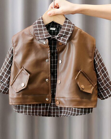 Un blouson en cuir marron sans manche avec une chemise à carreaux dessous, sur cintre, tenu par une main.