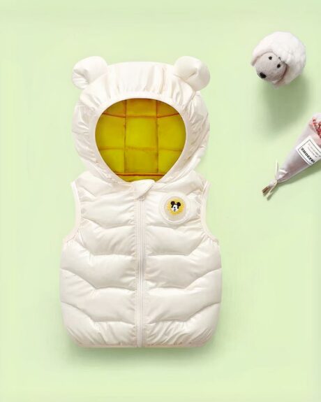 Doudoune sans manches pour enfant posé sur un fond vert.