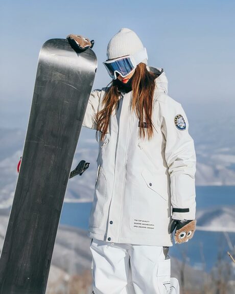 Blouson ski femme beige avec capuche porté par une fille en snowboard