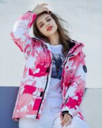Blouson ski femme rose et blanc avec capuche présenté sur une jeune femme
