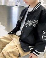 Blouson noir porté par un petit garçon assis, on ne voit ni sa tête ni ses jambes.