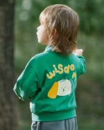 Un petit garçon qui porte un blouson teddy vert avec un chien dans le dos
