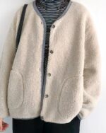 Une femme avec la tête coupée habillée d'un blouson chaud ample simple boutonnage beige