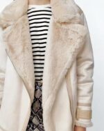 Blouson aviateur femme mi-long en simili cuir blanc et beige porté par une jeune femme dont on ne voit pas le visage