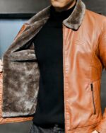 Blouson fourré avec col en fourrure synthétique en simili cuir porté par un homme sur fond gris