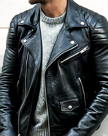 Homme avec le visage caché qui est adossé à un mur blanc portant un blouson simili cuir noir à col rabaissé