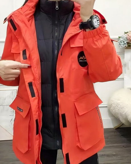 Une femme portant un blouson de ski rouge ouvert multi-poches
