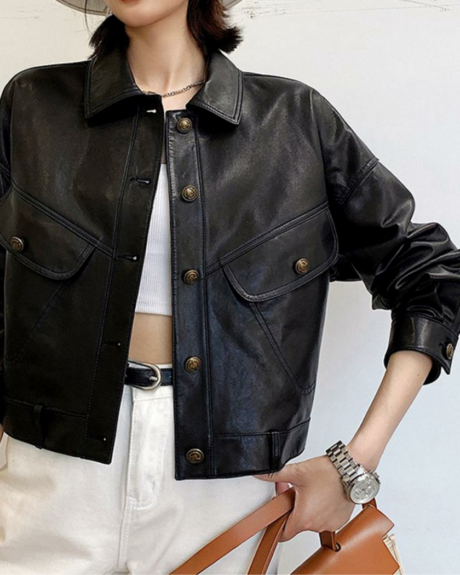 Une femme debout portant un blouson en cuir noir court ouvert