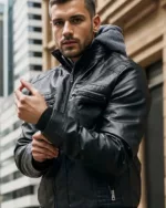 Un homme dans la rue qui porte un blouson simili cuir noir avec une capuche grise