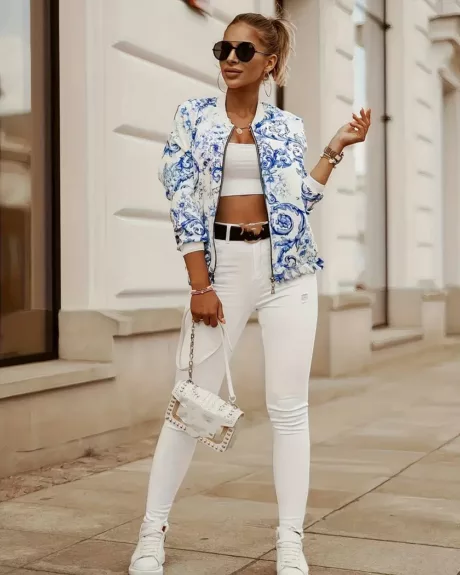 Une femme dans la rue portant un blouson court blanc à imprimé fleuri bleu vintage et un pantalon blanc