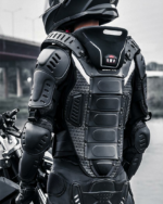 Un homme debout portant un blouson de moto noir multicoques et réfléchissant avec un casque noir sur la tête