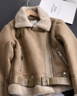 Un blouson style daim beige à col fourré posé sur une table