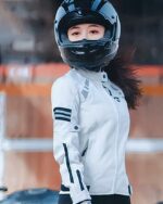 Une femme avec un casque sur la tête portant un blouson moto blanc