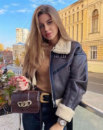 Une femme blonde dans la rue portant un blouson bombardier marron à col rabattu fourré
