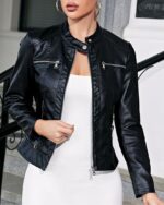 Une femme portant un blouson en simili cuir noir ouvert sur une robe blanche
