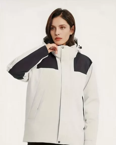 Une femme brune portant un blouson imperméable blanc et noir fermé avec col remonté