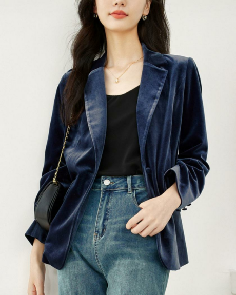 Une femme debout portant un blouson en velours bleu foncé ouvert à col rabattu