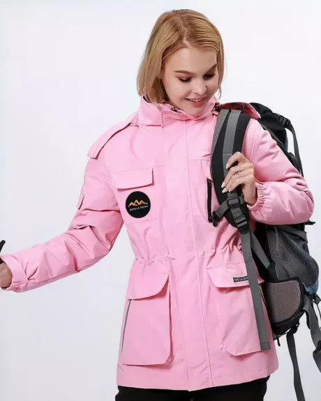 Blouson de ski rose pour femme porté par une femme blonde avec un sac à dos à l'épaule sur fond blanc