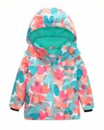 Blouson de ski pour fille avec des motifs de cœurs roses et bleus sur fond blanc. Le blouson dispose d'une capuche t son intérieur est bleu turquoise. Sur fond blanc.