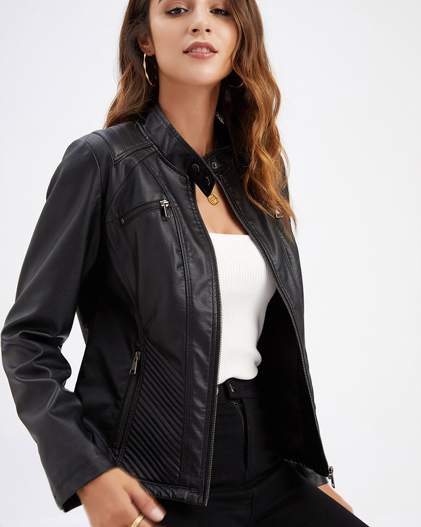 Une femme brune légèrement typée, portant un blouson perfecto femme en simili-cuir et coupe ajustée de couleur noir par dessus un t-shirt blanc, sur un fond blanc studio.