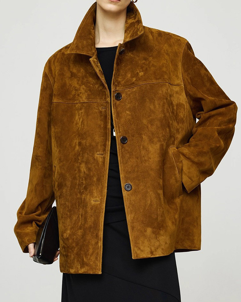 Une femme dont on ne voit pas la tête portant un blouson en velours côtelé oversize pour femme de couleur marron, sur une robe noire, portant un petit sac à main noir sans bandoulière.